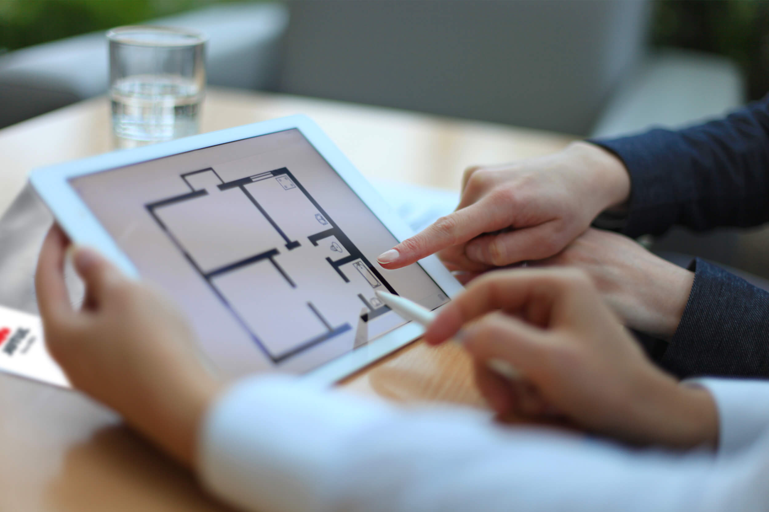 Kädet osoittavat iPadia talon huonejakaumataulukolla.