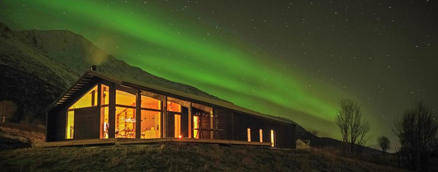 Moderni mökki vuorella revontulien valossa