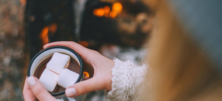 Tyttö juo kaakaota tulen äärellä