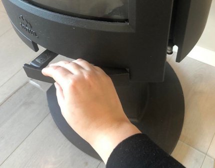 Käsi, joka avaa takkaluukun puukiukaan Jøtul F 373 Edistä varovasti 