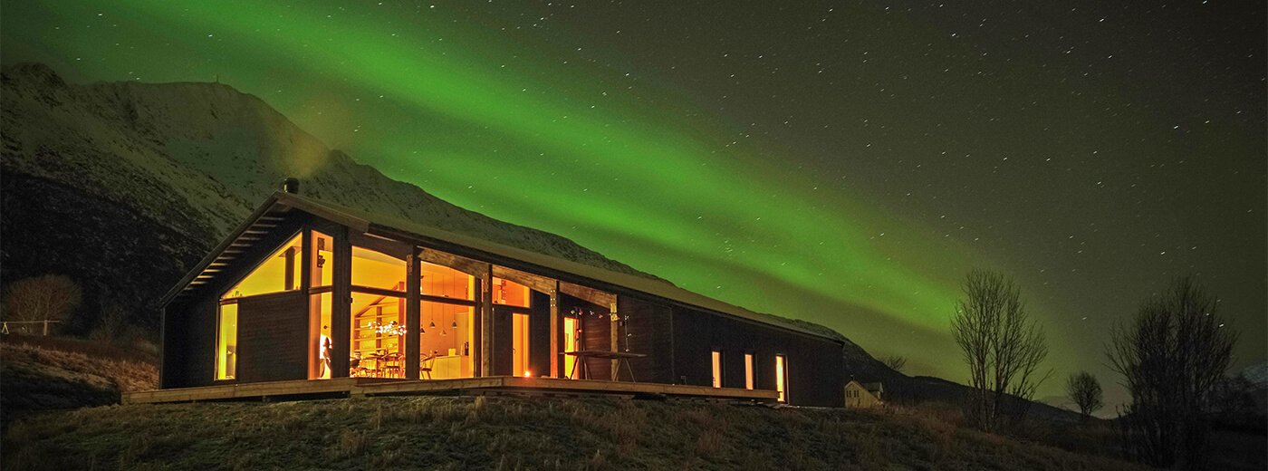 Moderni mökki vuorella revontulien valossa