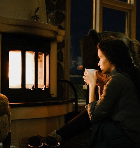 Nainen istuu takan edessä illalla